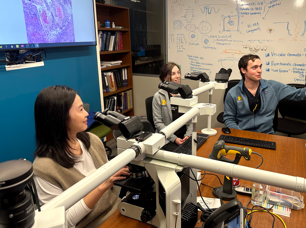 Dr. Grace Wang (left) working with two fellows in the Dermatopathology sign-out room.